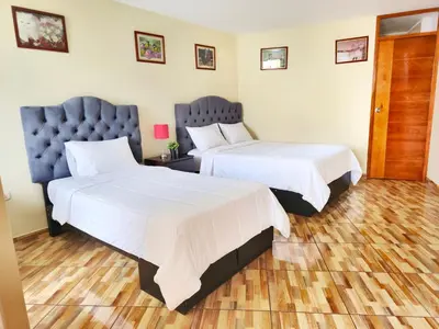 two beds in a hotel room with white sheets at Hospedaje Celerina & Elio in Lima