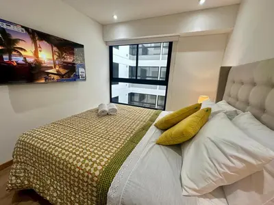 a bedroom with a bed with yellow pillows and a window at Moderno Departamento de 2 dormitorios a solo 6 min del Parque Kennedy Miraflores in Lima
