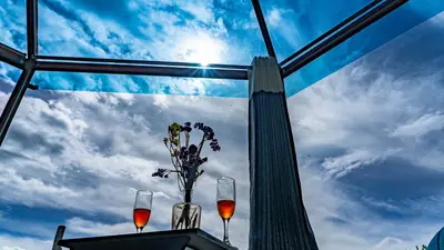 a table with two glasses and a vase with flowers at Sky Dome Peru in Cusco