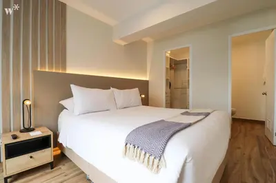 a bedroom with a large white bed and a night stand at Colon by Wynwood House in Lima