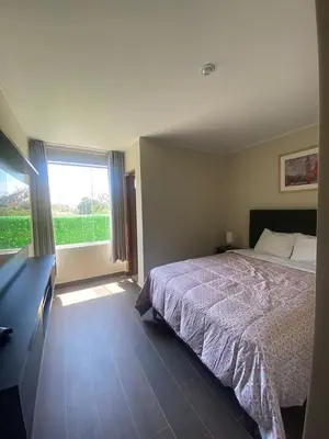 a bedroom with a bed and a dresser and a window at Hotel Nebai in Ica