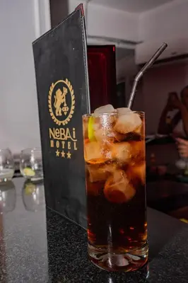 a drink sitting on a table with a book at Hotel Nebai in Ica